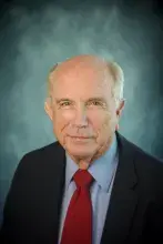 Headshot of man with dark suit and red tie