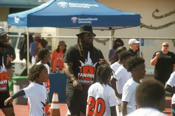 Marshawn Lynch surrounded by young athletes