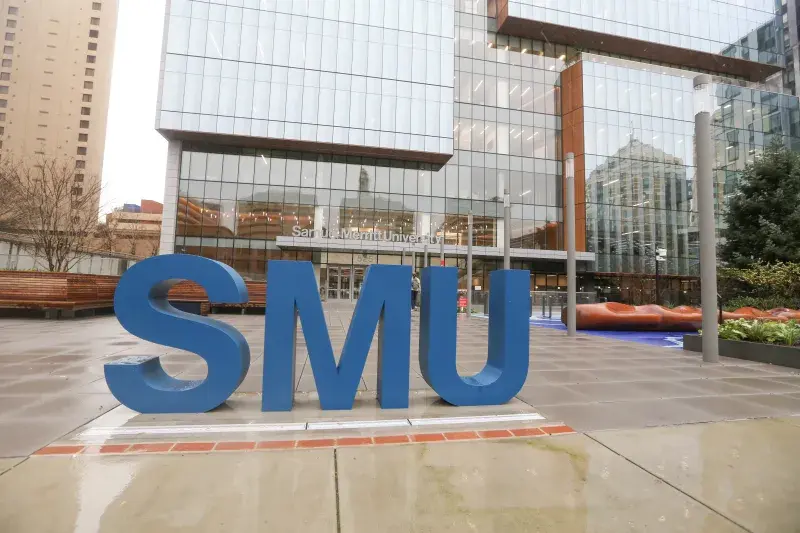 Exterior of the SMU Oakland campus. Large blue "SMU" is in the foreground.