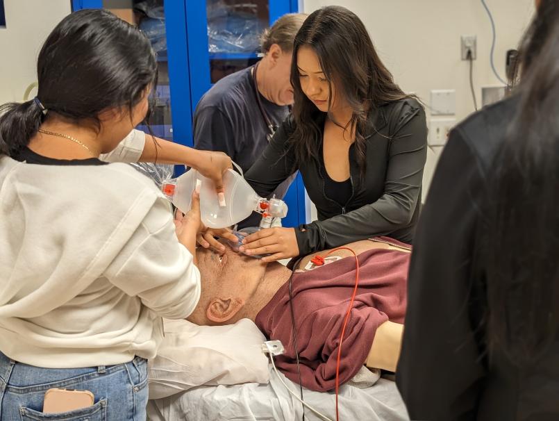 Students gather around a mock patient in a simulation center.