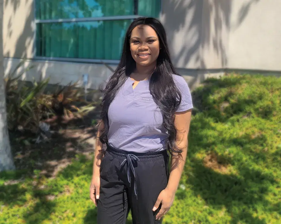SMU student Keamiyah Walker stands outdoors wearing lavender top and black scrub pants.
