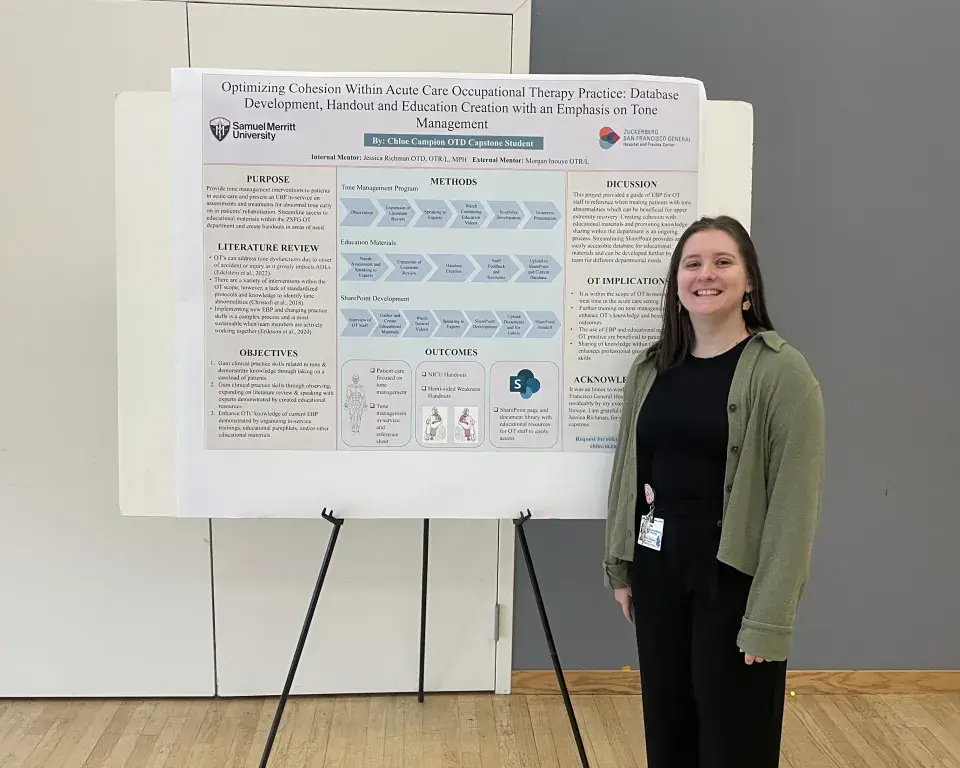 Occupational Therapy student stands in front of poster with class project.