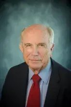 Headshot of man with dark suit and red tie