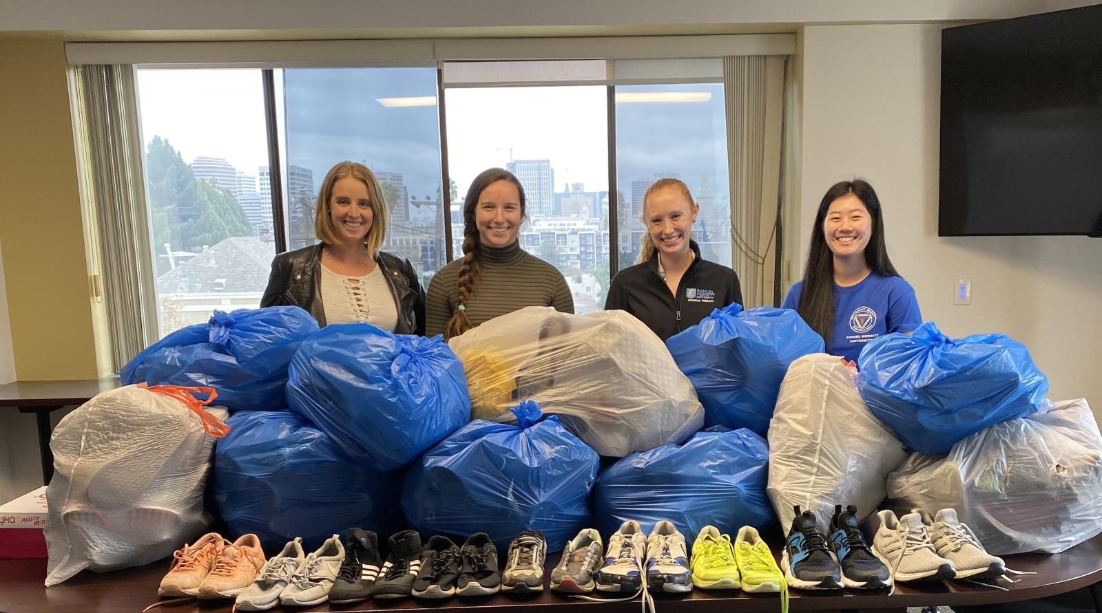 (4) DPT students and the shoes collected from the shoe drive.