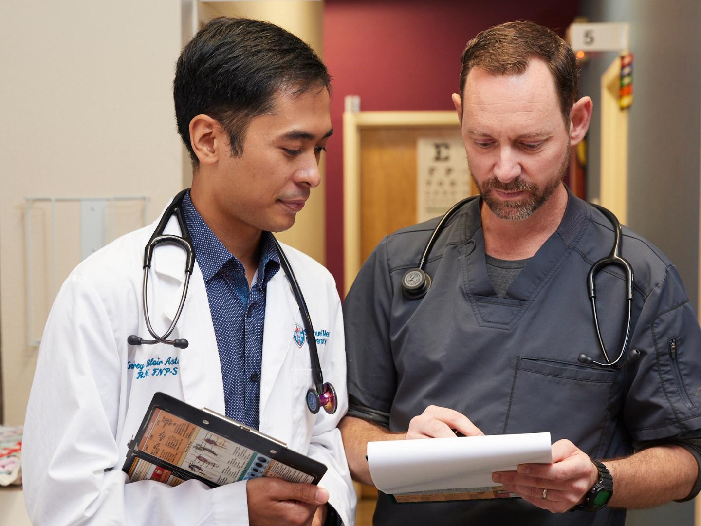 Two male nurses looking at clipboard in clinic