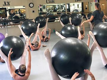 Aimee Martel, DPT '07, (standing) leads yoga ball exercises with a group of dancers.