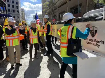 President Wang signs the beam near the SMU logo, others in safety gear stand nearby.