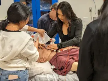 Students gather around a mock patient in a simulation center.