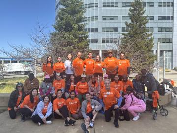 20+ people in orange shirts posing.