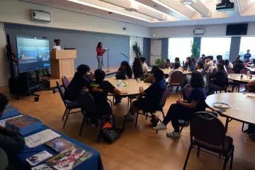 Students gather at round tables to engage in reading session.