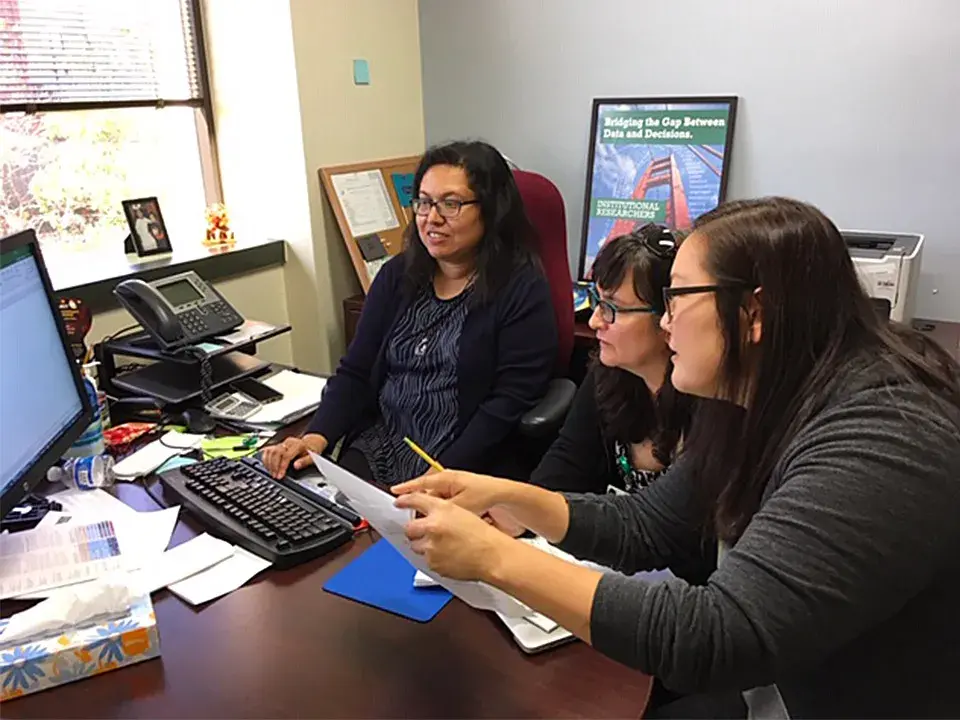 Students review statistical data on a computer screen.