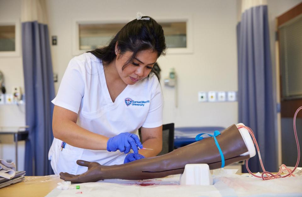 Nurse practicing on a fake arm drawing blood