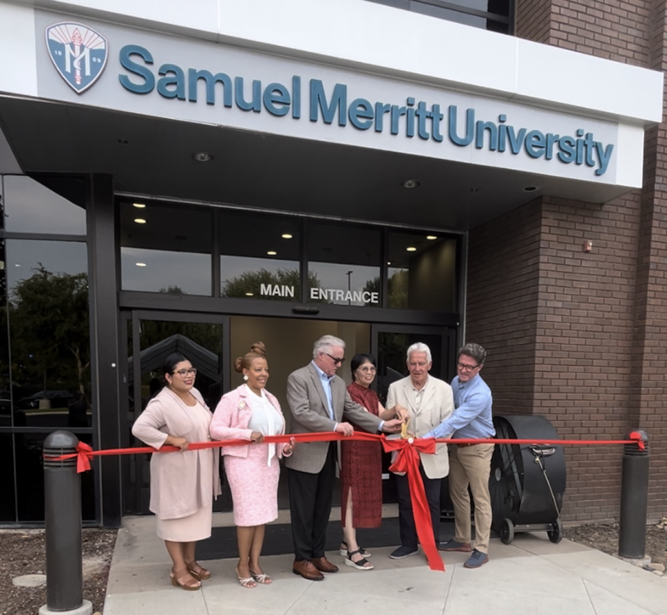 6 people standing in front of the SMU campus in Fresno cutting a ribbon.