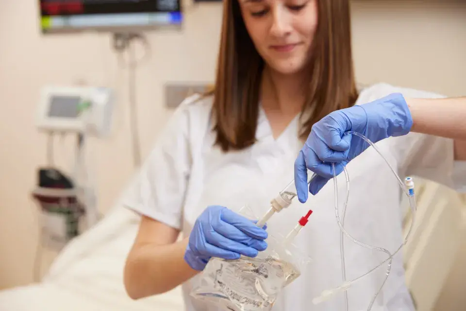 Nurse wearing gloves with IV bag.